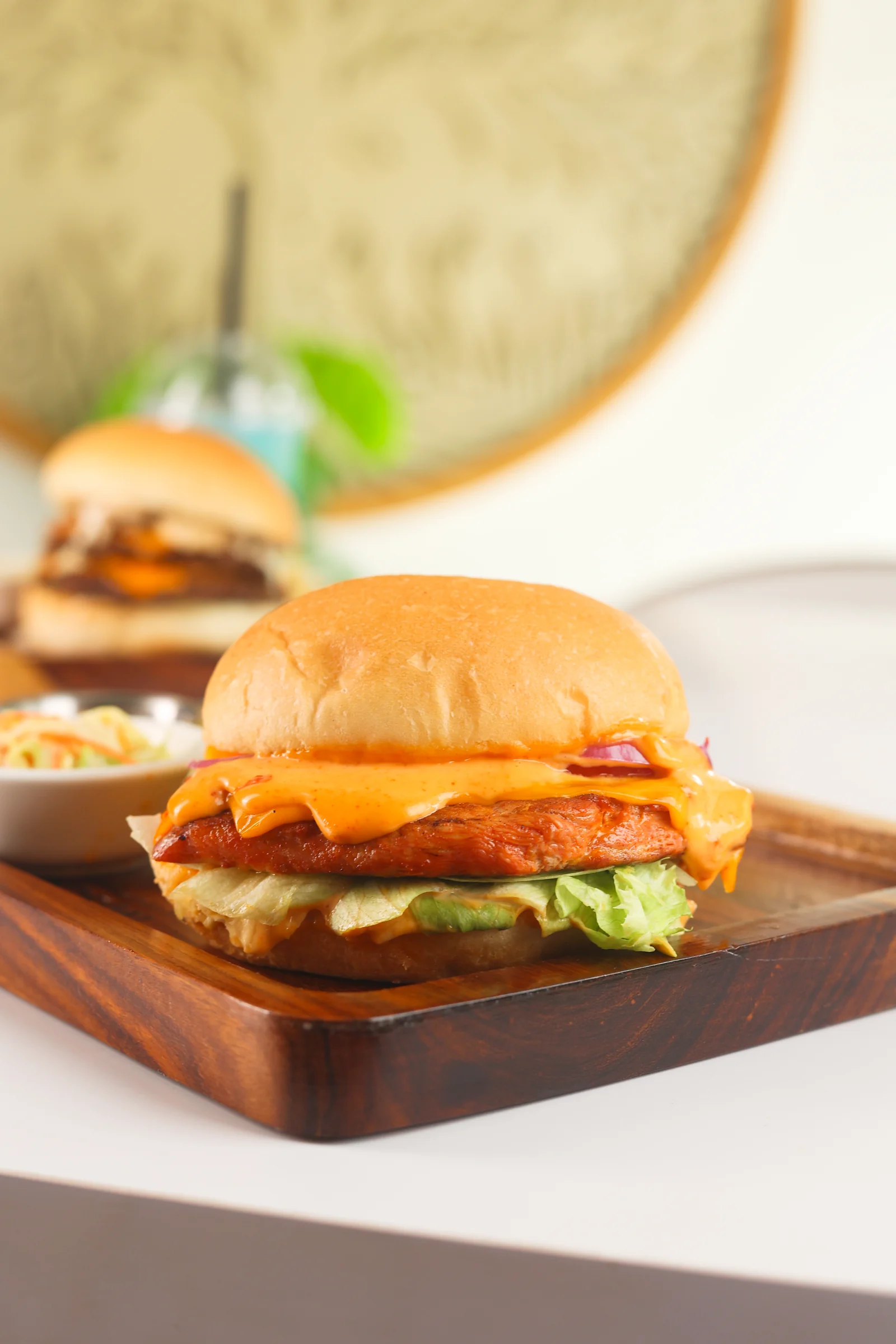 Golden chicken burger with melted cheese and lettuce on a wooden board
